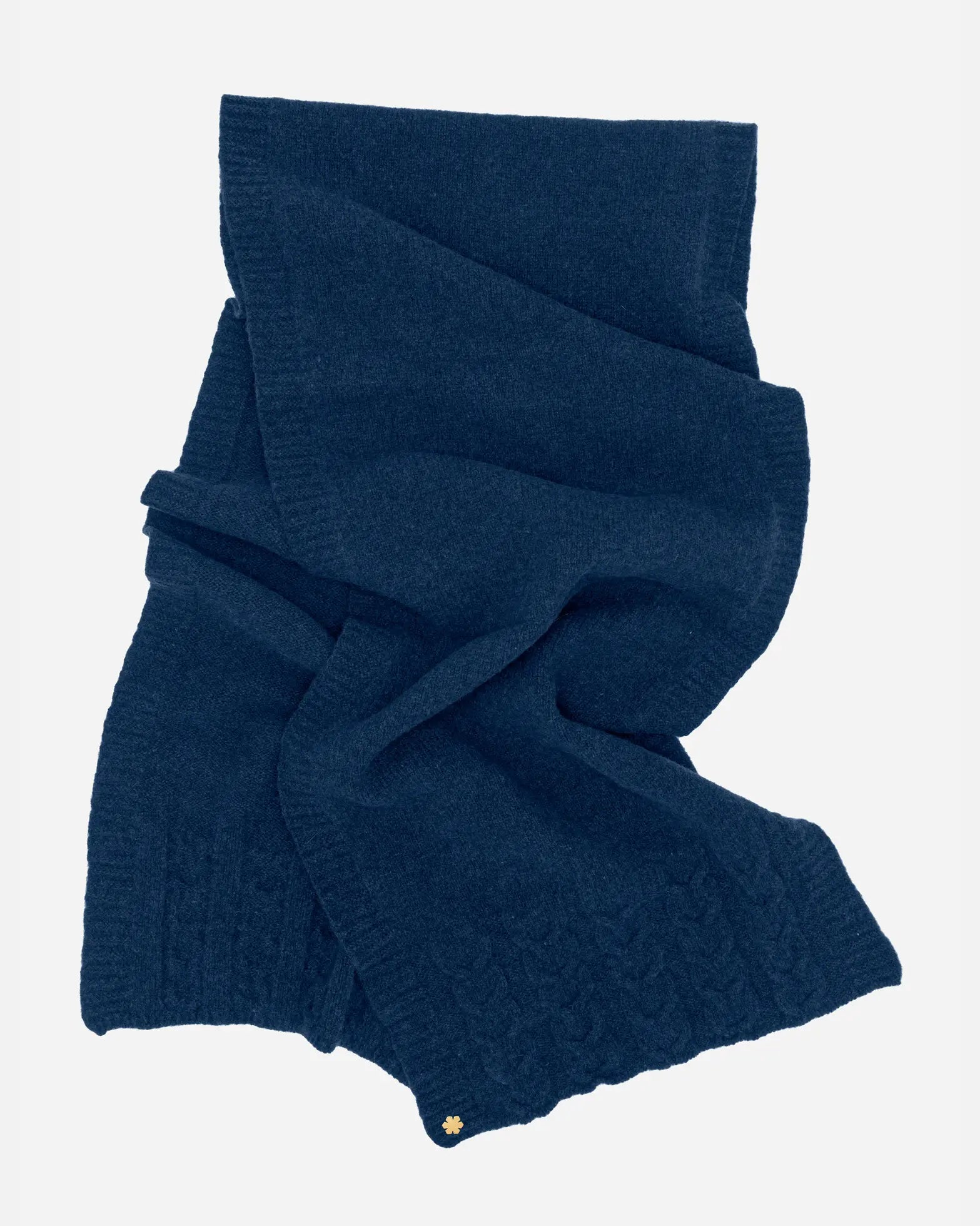 Arie Tørklædet i farven atlantic blue prydet med strikkede detaljer og en 14 karat forgyldt Kalmus blomst i det ene hjørne.