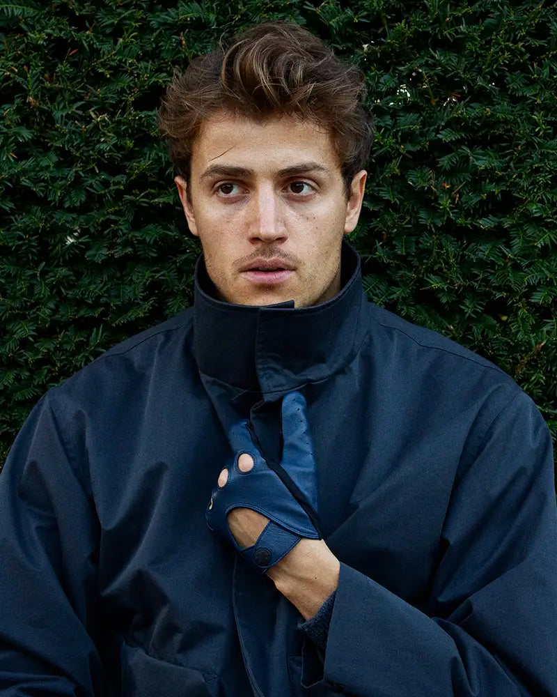 One-size kørehandsker til mænd fra RHANDERS. Fremstillet af lammeskind i en smuk mørkeblå farve, prydet med en matsort Kalmus knap.