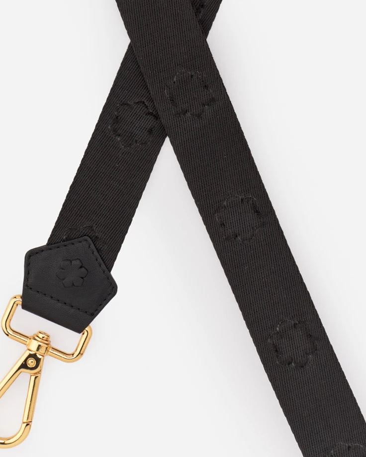 Kalmus Emboss Strap fra RHANDERS er en unik skulderrem, præget med Kalmus-blomsten i stoffet og med guld spænder.