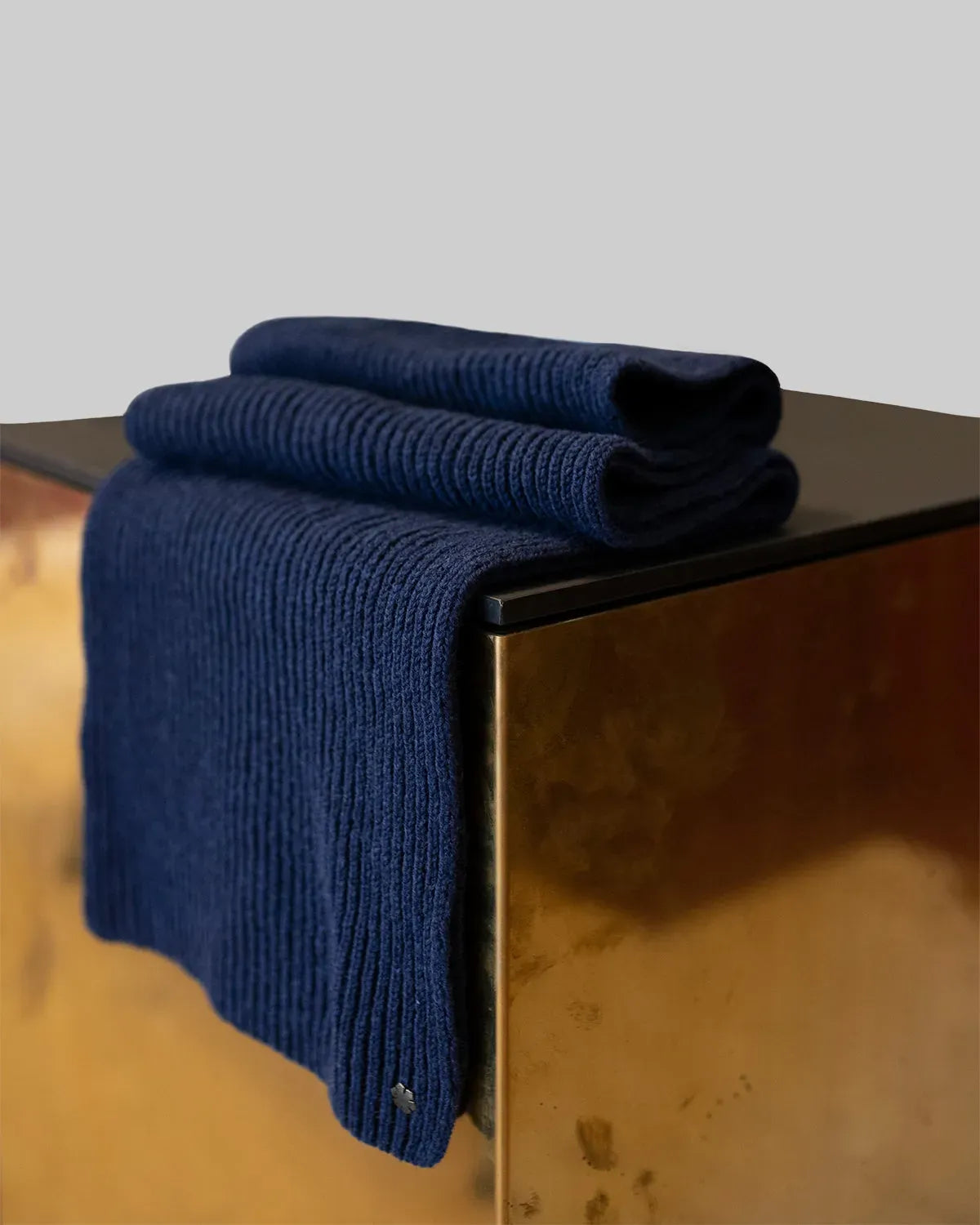 The Alex Scarf for men in the colour atlantic blue adorned with a hematite-plated Kalmus flower in one corner.
