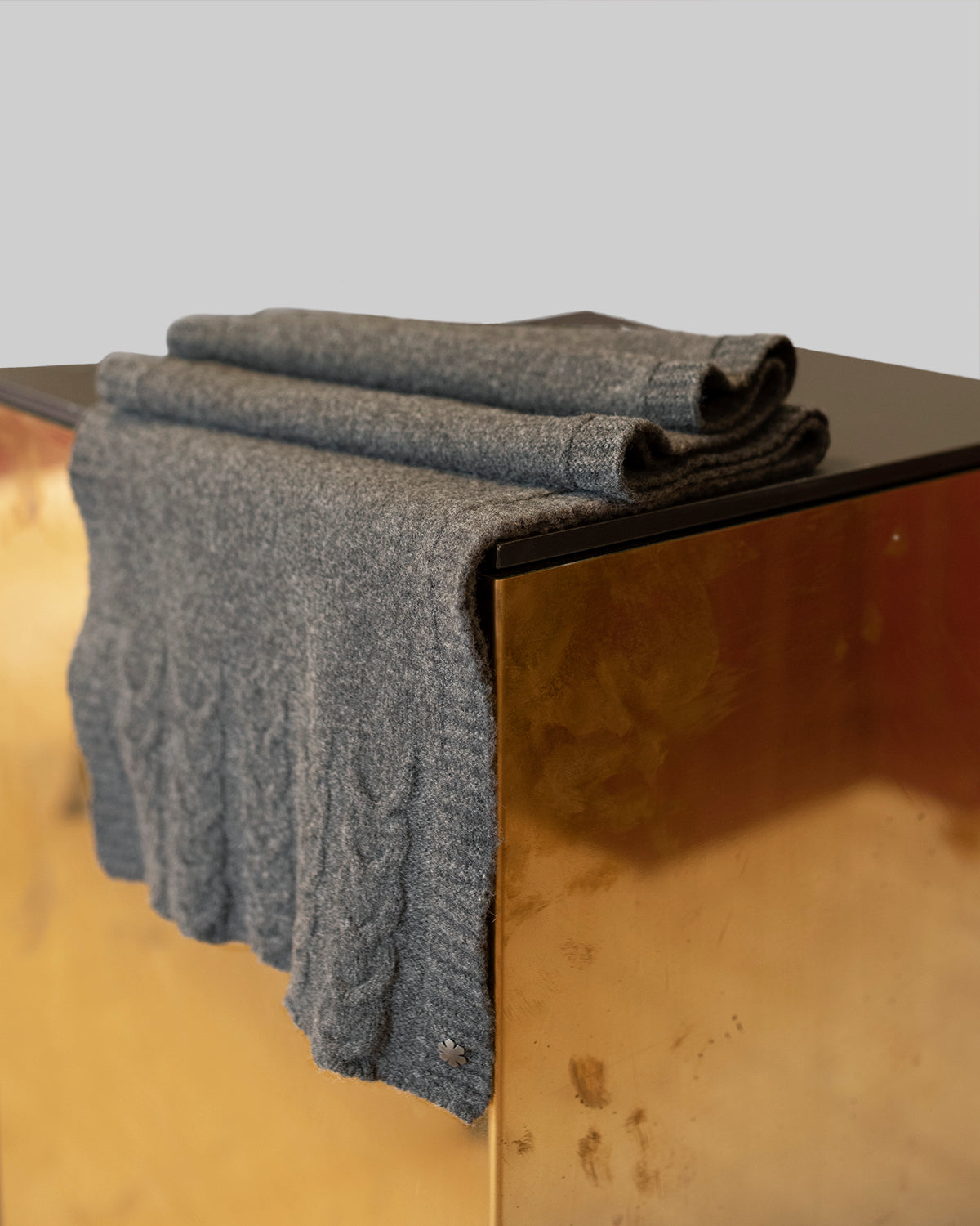 Light grey Arie Scarf adorned with knitted details and a hematite-plated Kalmus flower in one corner.