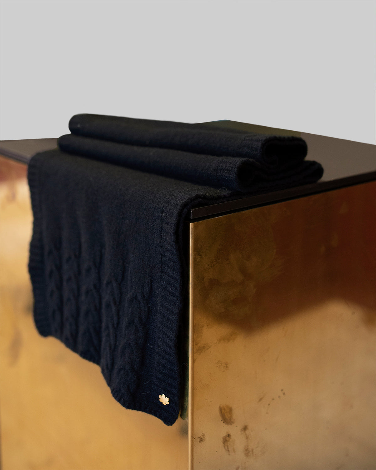 Navy Arie Tørklæde prydet med strikkede detaljer og en 14 karat forgyldt Kalmus blomst i det ene hjørne.