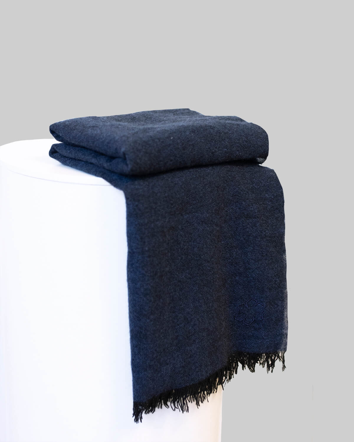 Aston unisex scarf from RHANDERS in the colour navy adorned with an embroidered outline Kalmus flower in one corner.
