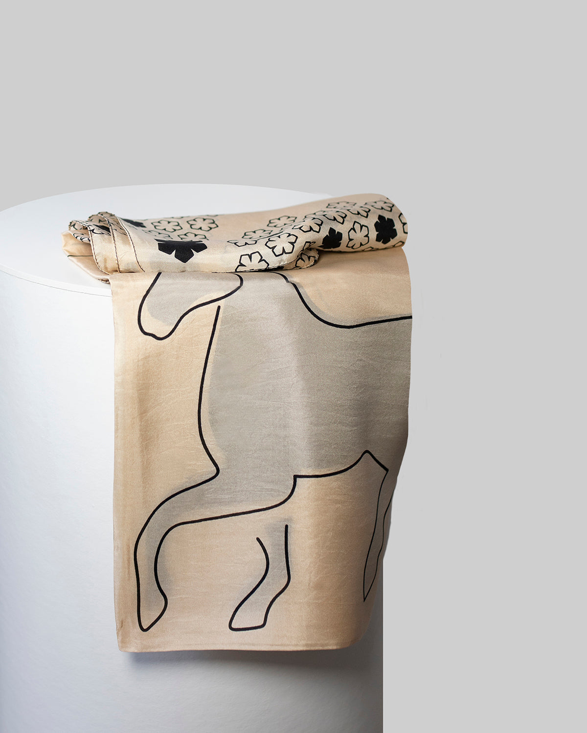 Cheval Tørklædet til kvinder fra RHANDERS prydet med fire grafiske heste på en champagnefarvet baggrund med sorte detaljer.