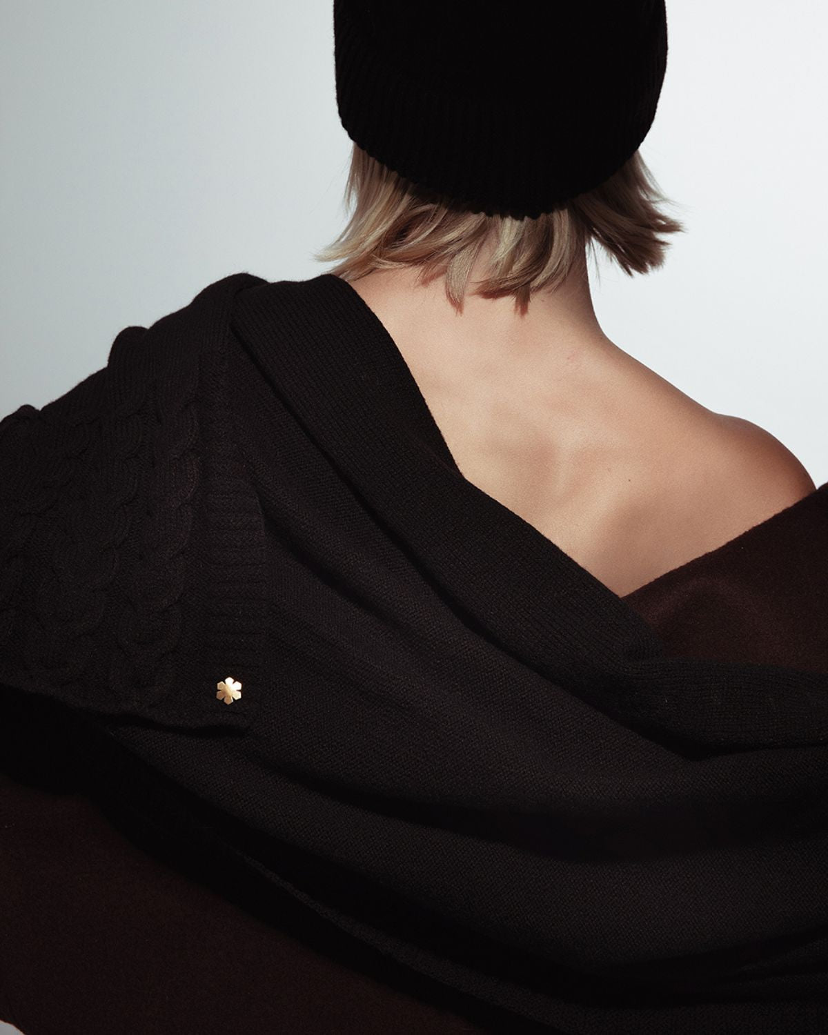 Black Arie Grand Scarf adorned with knitted details and a 14 karat gold-plated Kalmus flower in one corner.