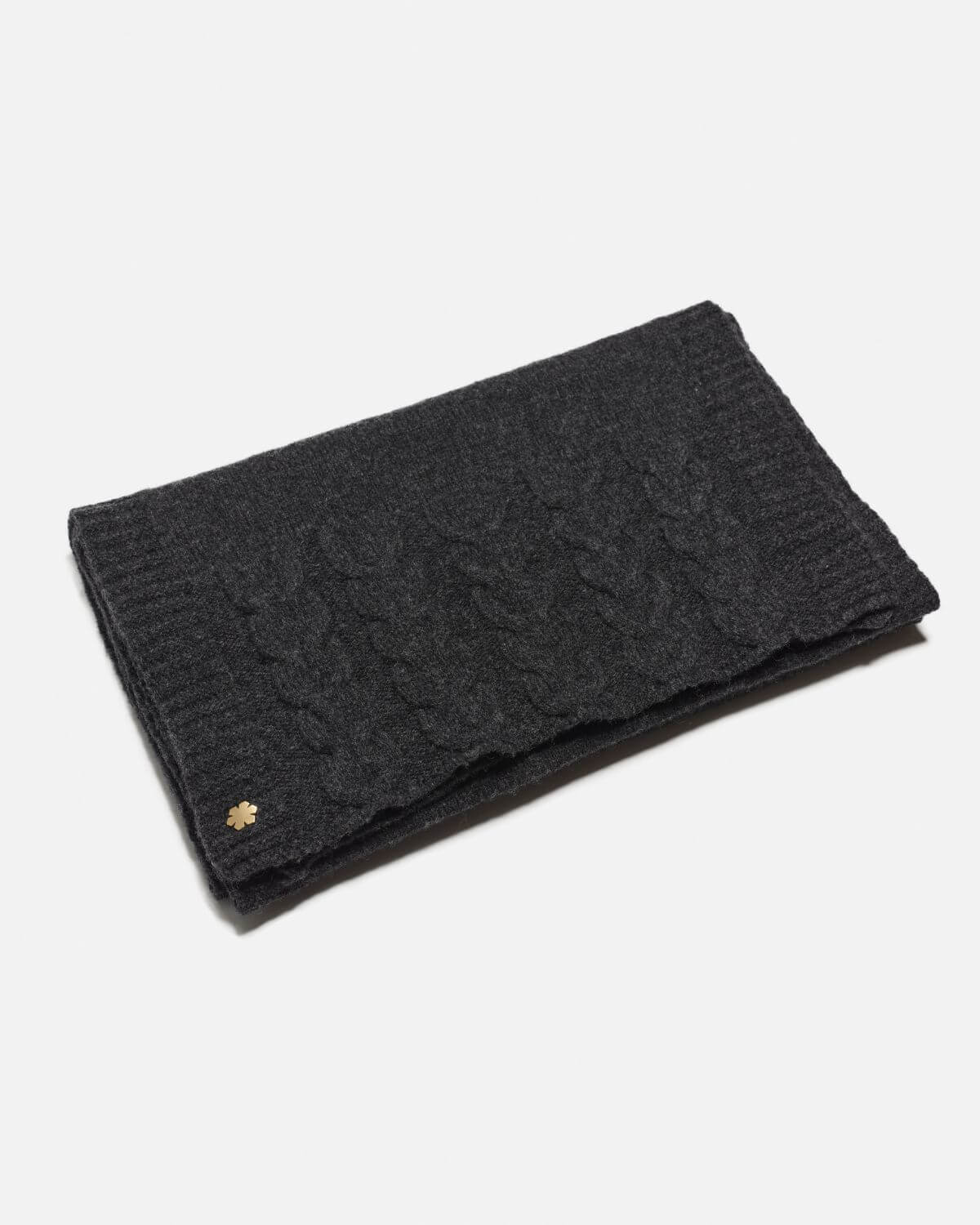 The Arie Scarf in the colour charcoal adorned with knitted details and a 14 karat gold-plated Kalmus flower in one corner.