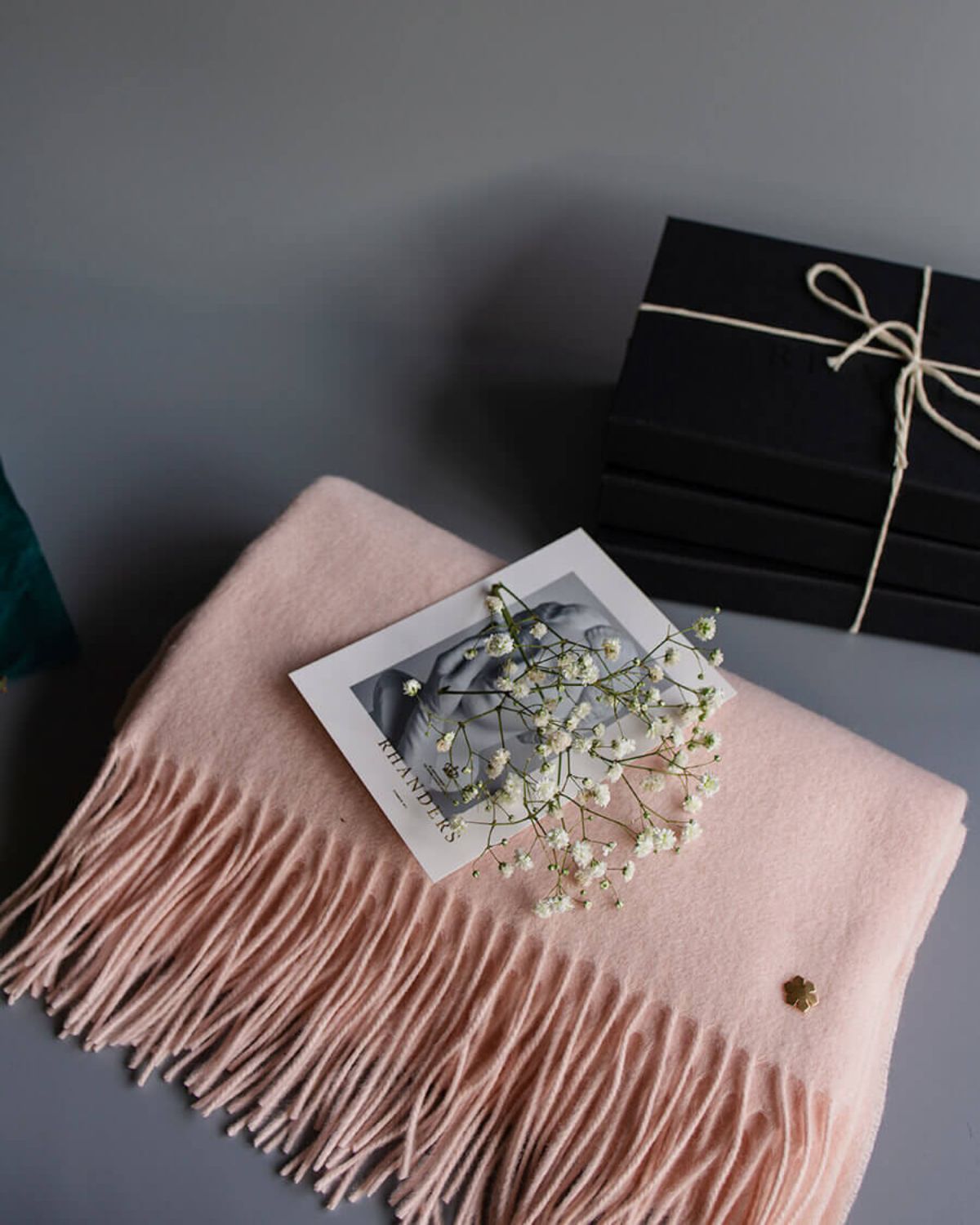 The Aurora wool scarf for women in the colour pink champagne adorned with a 14 karat gold-plated Kalmus flower in one corner.