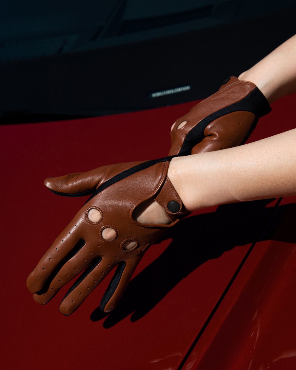 Unlined women’s driving gloves from RHANDERS, crafted from lamb leather with panels of Lycra for elasticity.