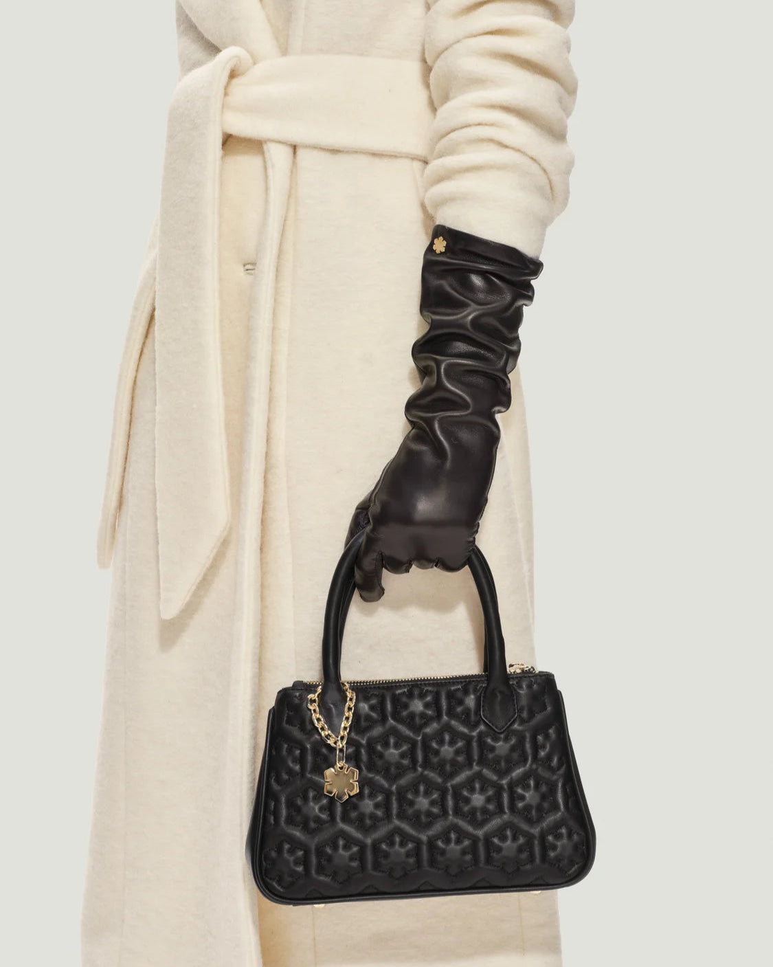 Elegant Isabella håndtaske fra RHANDERS i sort med quilted og vatteret med Kalmus blomstermønster samt polstrede hanke, der afsluttes smukt i form af et Kalmus blad.