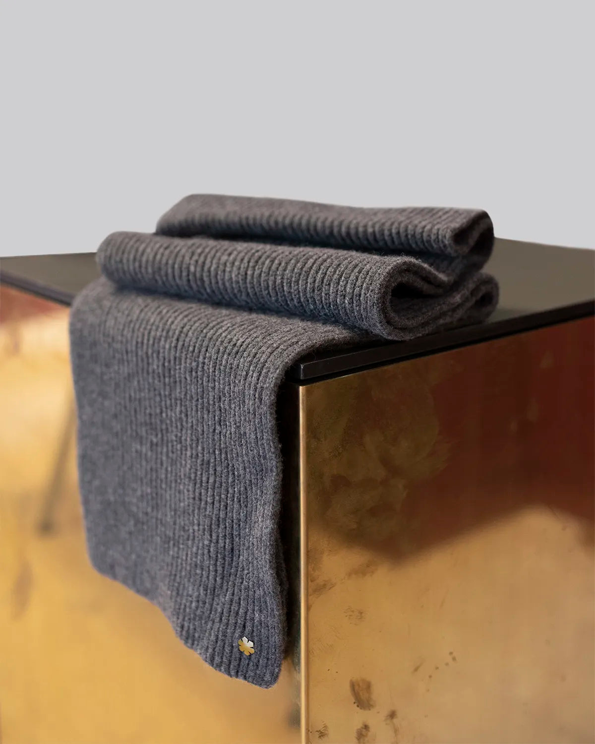 Light grey Alex Scarf for women adorned with a 14 karat gold-plated Kalmus flower in one corner.