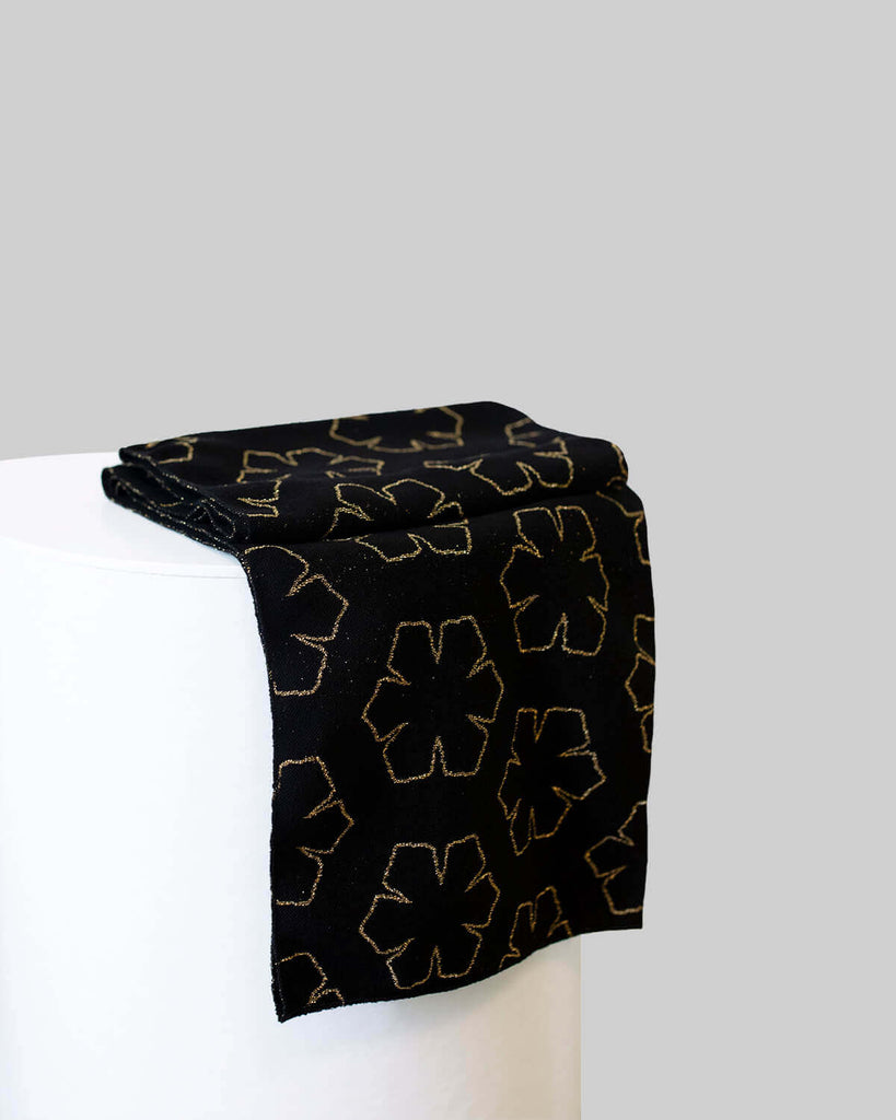 Smukt og blødt uld tørklæde til kvinder i farven sort med mønster af guld kalmus-blomster.